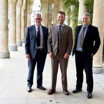 Three men in suits standing in UQ's Great Court. 